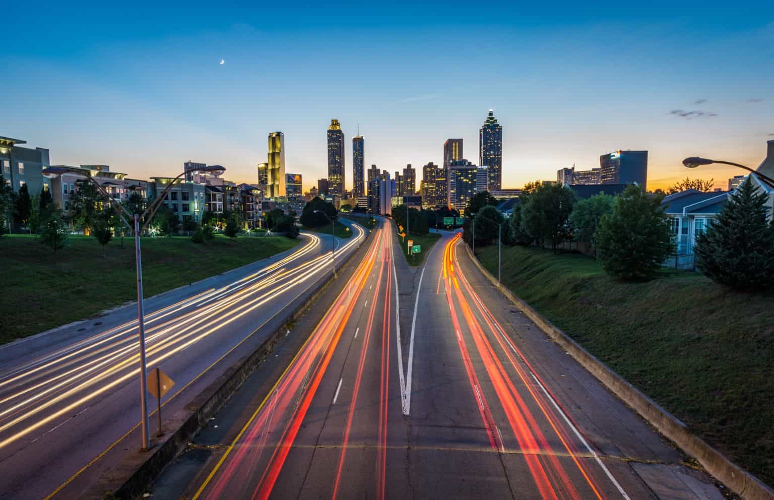 City skyline at night with long exposure light trails from cars and blurry clouds