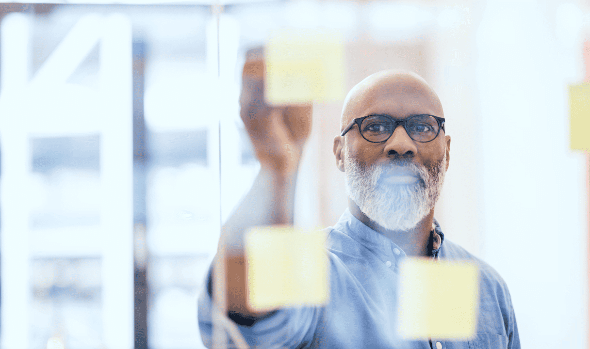 Man sticking notes about IT Cost Reduction